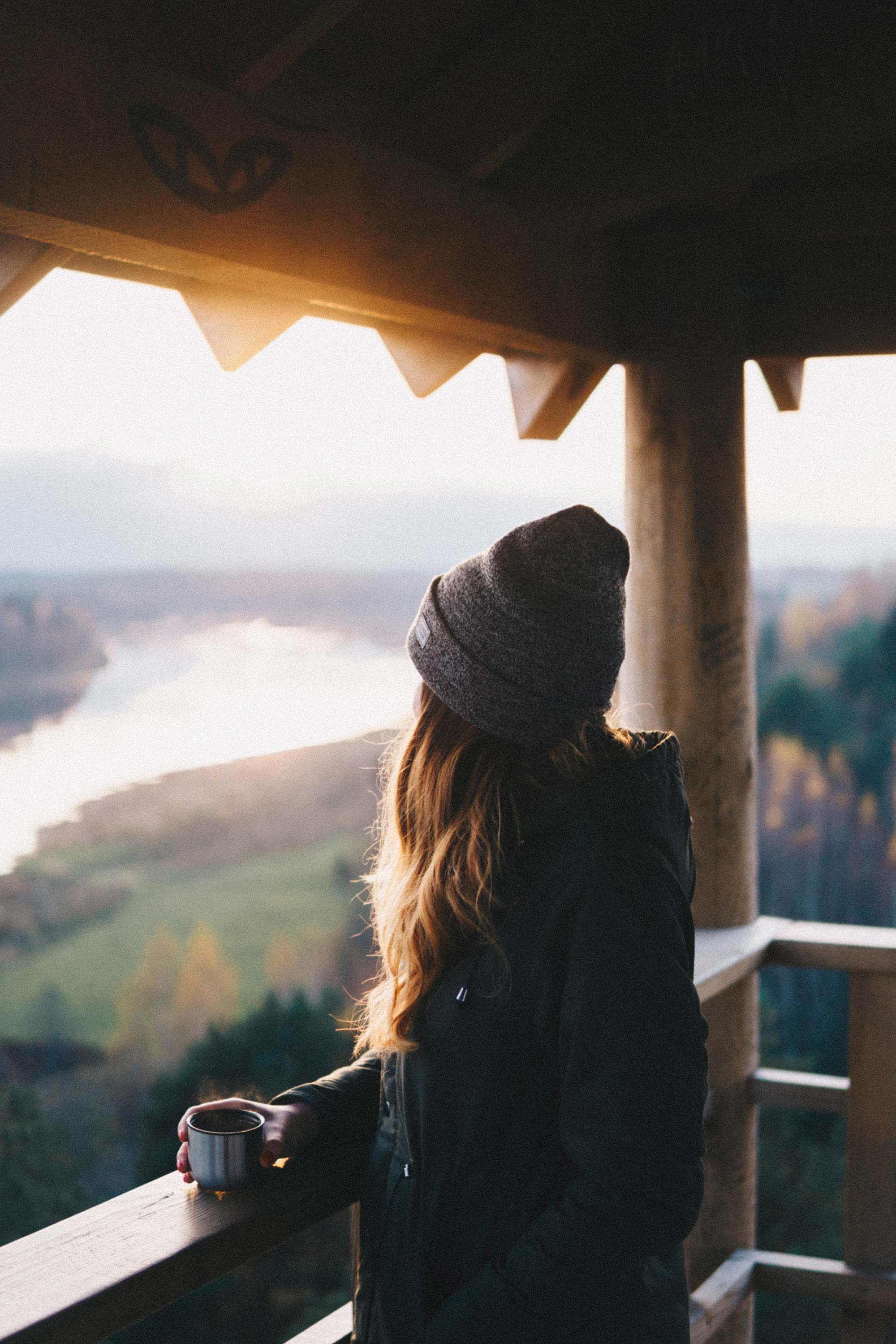 Frau geniesst Aussicht auf weitläufige Landschaft vom Balkon
